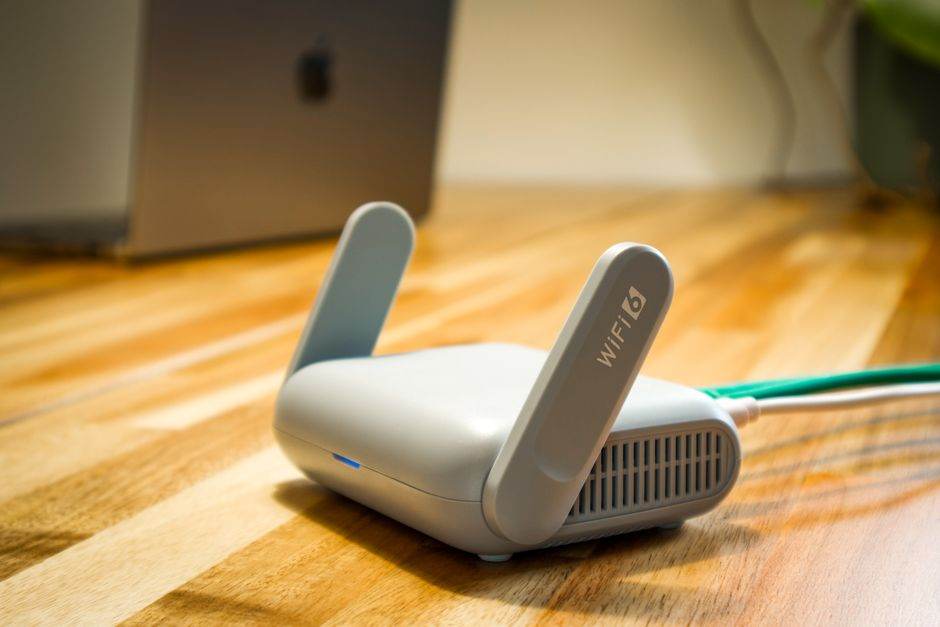 A sleek WiFi 6 router with antennas and cable on a wooden desk, perfect for modern home networks.