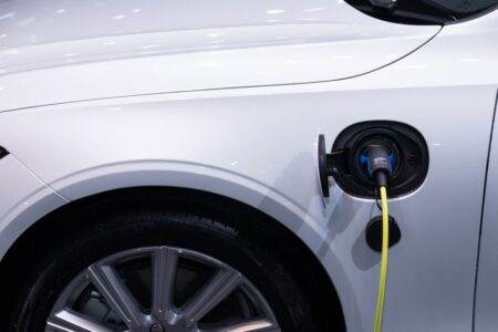 Hybrides rechargeables : l’usage creuse l’écart d’émissions A white electric car is plugged in for charging, close-up view of the charging port.