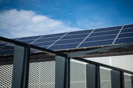 Close-up view of modern solar panels on a rooftop against a clear blue sky, representing clean energy.