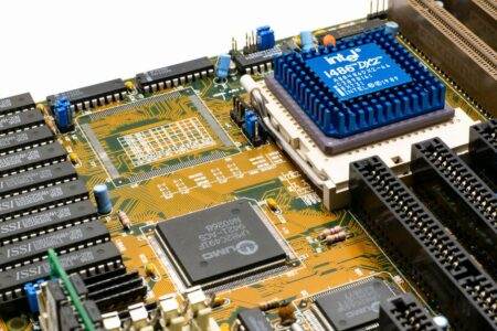 Architecture des processeurs en 2026 : l’ISA après le matériel Detailed view of an Intel i486 DX2 CPU installed on a vintage motherboard with chips and circuits.