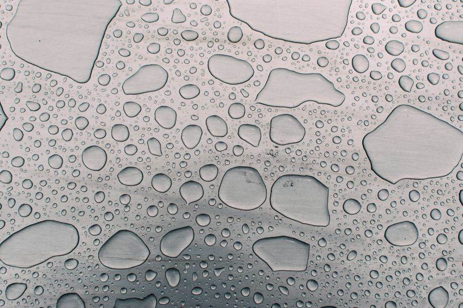 Detailed view of water droplets forming patterns on a metallic background, highlighting texture and clarity.