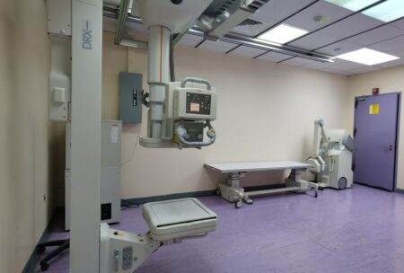 Hôpitaux américains : l’imitation des services a ses limites Interior view of a well-equipped hospital X-ray room with medical imaging devices.