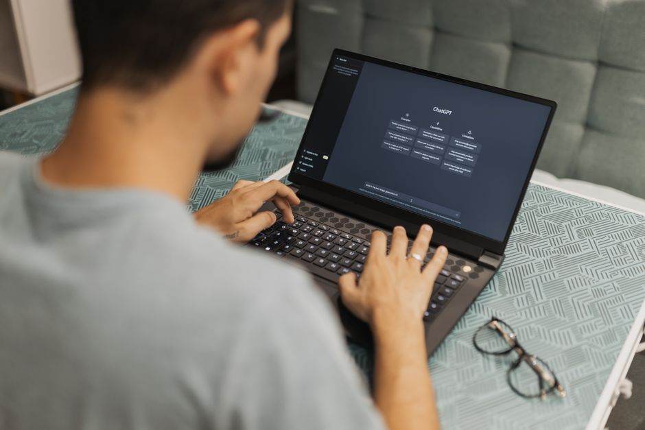 Superintelligence en 2026 : le terme qui brouille l’IA Man using laptop with AI interface, typing with focused attention. Indoors with eyewear beside.