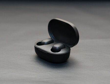 Aides auditives Anker : le réglage à domicile reste assisté Modern wireless earbuds in an open black charging case on a matte surface.