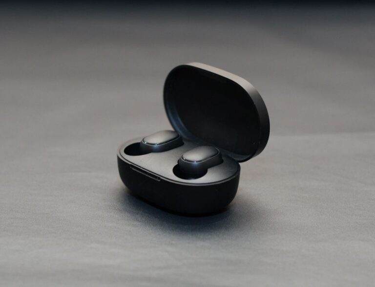 Aides auditives Anker : le réglage à domicile reste assisté Modern wireless earbuds in an open black charging case on a matte surface.