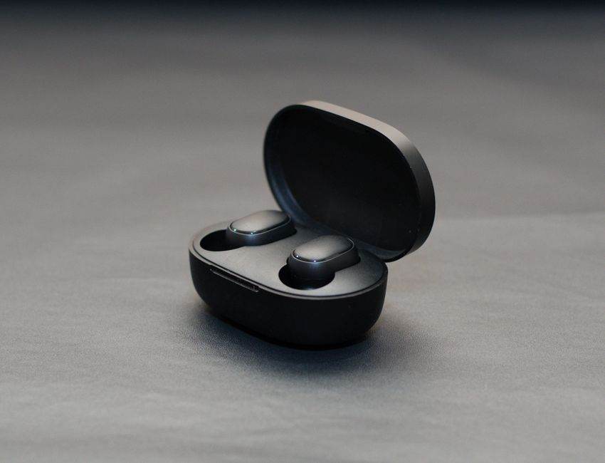 Aides auditives Anker : le réglage à domicile reste assisté Modern wireless earbuds in an open black charging case on a matte surface.