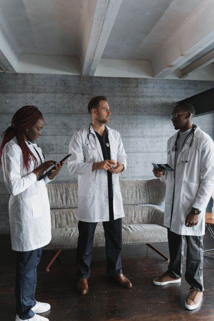 Three healthcare professionals in discussion at a hospital setting.