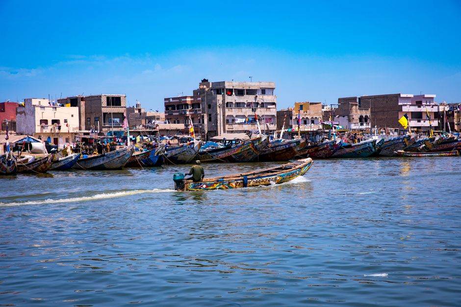 Vibrant fishing boats lined along a bustling coastal village with bright blue skies, encapsulating a lively marine scene.