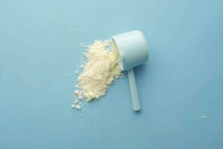 Bicarbonate de sodium : réanimation, sport, rein et linge White powder spilled from a scoop on bright blue background. Clean and minimalistic food photo.