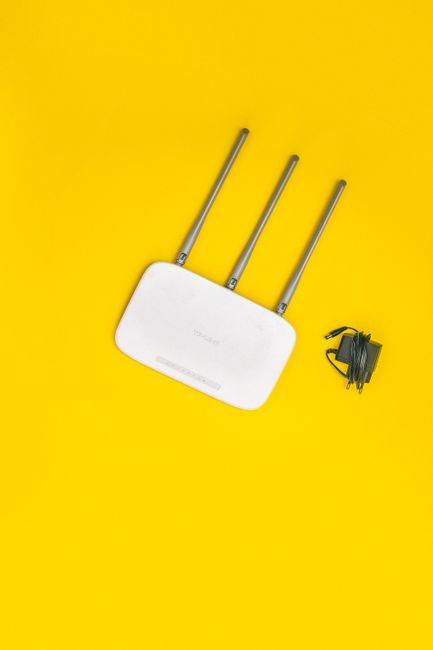 White router with three antennas and cables on bold yellow background, ideal for tech concepts.