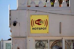 Yellow WiFi hotspot sign on a building facade in Cala Rajada, perfect for connectivity themes.