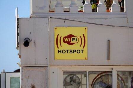 Yellow WiFi hotspot sign on a building facade in Cala Rajada, perfect for connectivity themes.