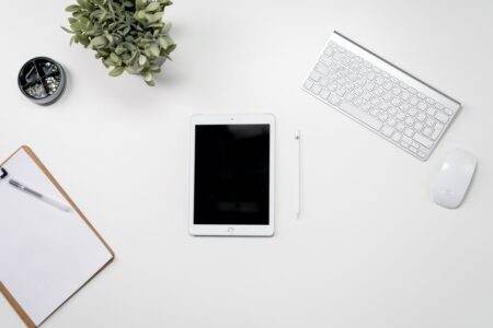 Honor Pad 20 Pro : une tablette face au PC portable A clean home office desk setup featuring a tablet, keyboard, mouse, and plant for inspiration.