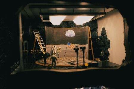 Artémis II : ce que la rumeur des radiations ne prouve pas A creative diorama depicting the moon landing with astronauts and flag in a studio setup.