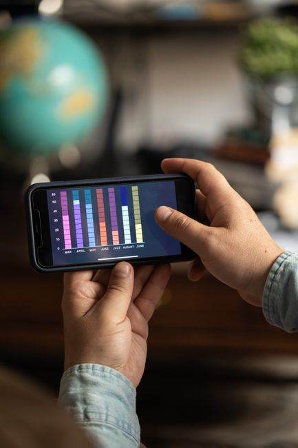 Close-up of a smartphone displaying colorful data charts held by hands, showcasing digital analytics.