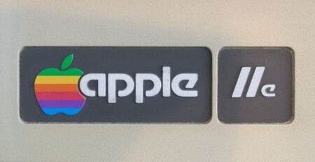 Apple-1 : le refus de 400 dollars et le record à 1,15 million Close-up of retro Apple IIe computer logo featuring rainbow apple symbol, showcasing vintage technology design.