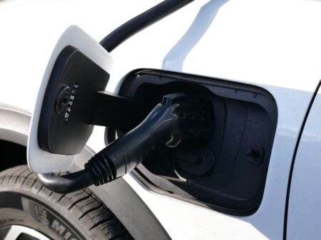 Renault vise 750 km pour les futurs Scénic et Rafale électriques Close-up view of an electric vehicle charging with a focus on the connector and charging port.