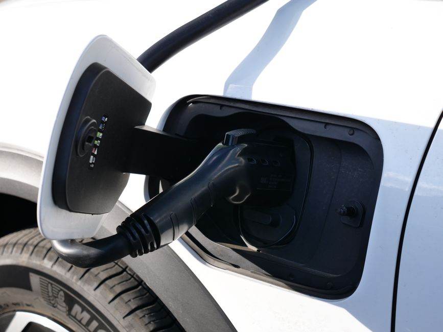 Renault vise 750 km pour les futurs Scénic et Rafale électriques Close-up view of an electric vehicle charging with a focus on the connector and charging port.