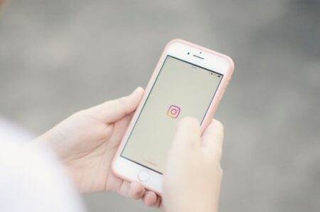 Clavier iPhone : 9 gestes et réglages utiles Hands holding a smartphone with the Instagram app open on the screen.