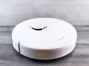Sleek white robot vacuum cleaner on a wooden floor, perfect for smart home setups.