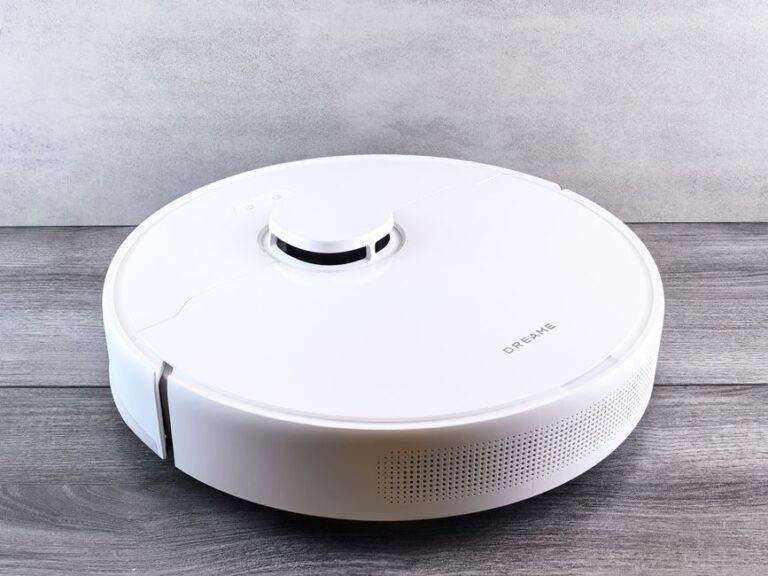 Dreame X60 Pro Ultra Complete : test, prix et limites Sleek white robot vacuum cleaner on a wooden floor, perfect for smart home setups.