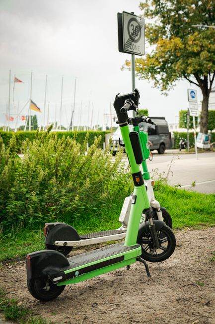 Two electric scooters parked near a road with a speed limit sign, showcasing urban mobility in Hamburg.