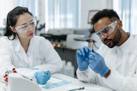 Une preuve prometteuse ne suffit pas : le terrain tranche Two scientists in protective gear analyze blood samples in a laboratory setting.